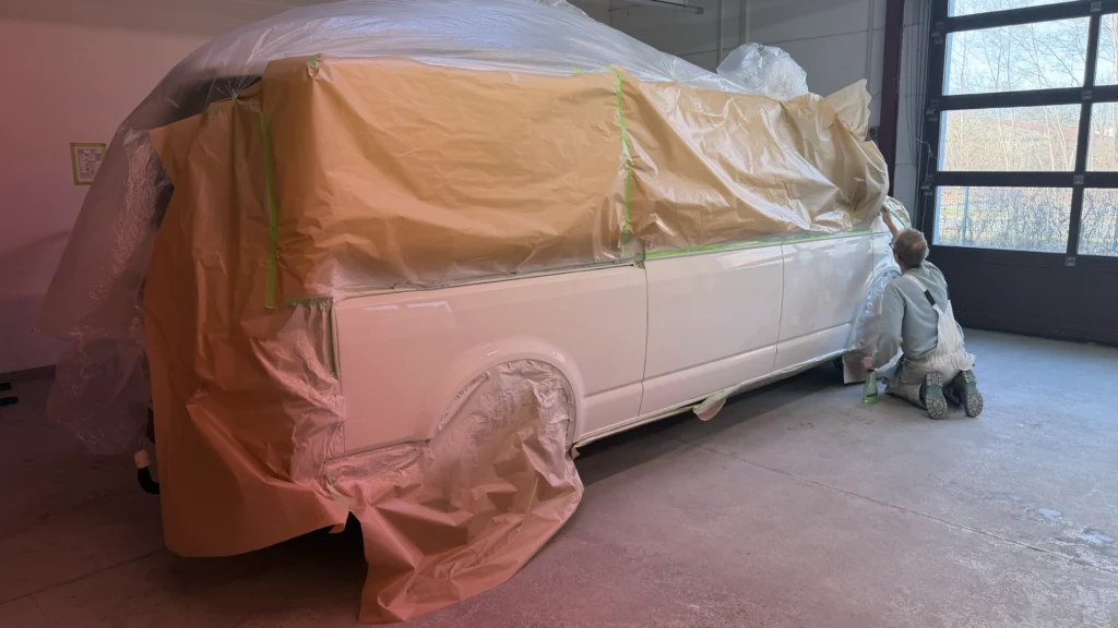 Lackierer prüft die lackierten Flächen am Fahrzeug.