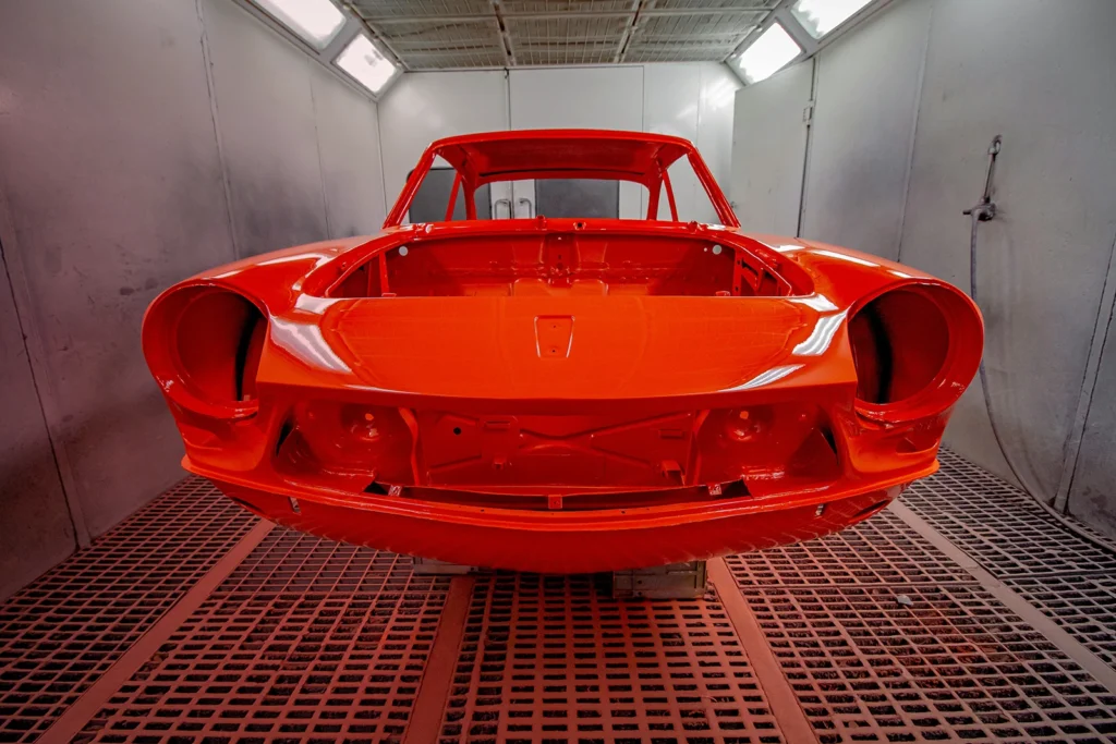 Ein in Rot lackiertes Auto steht in der Lackierkabine zum Trocknen.